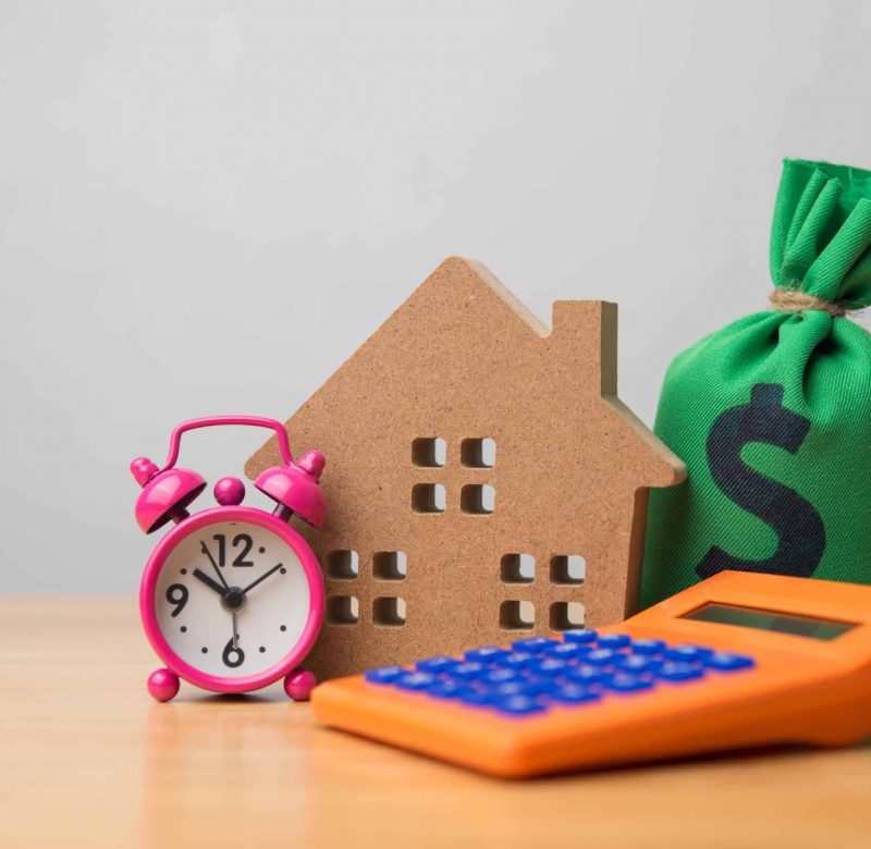 A home, bag of money, calculator and alarm clock signifying time to use CEMA for mortgage consolidation.